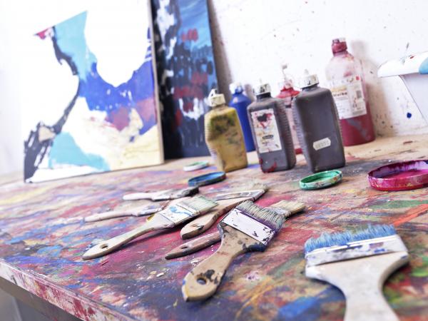 Werbebild für Kunstkurse allgemein: Farben und Werke auf Tisch mit Pinseln